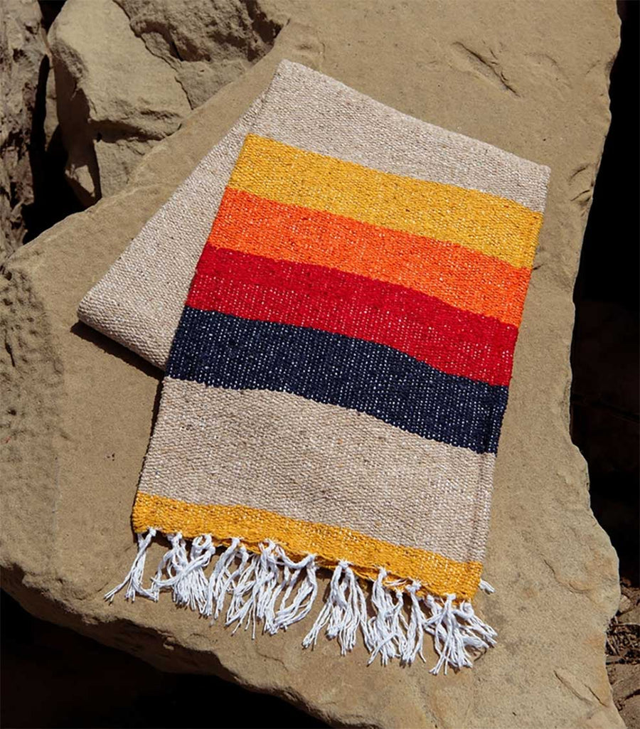 Colorful woven blanket with striped pattern on a rock