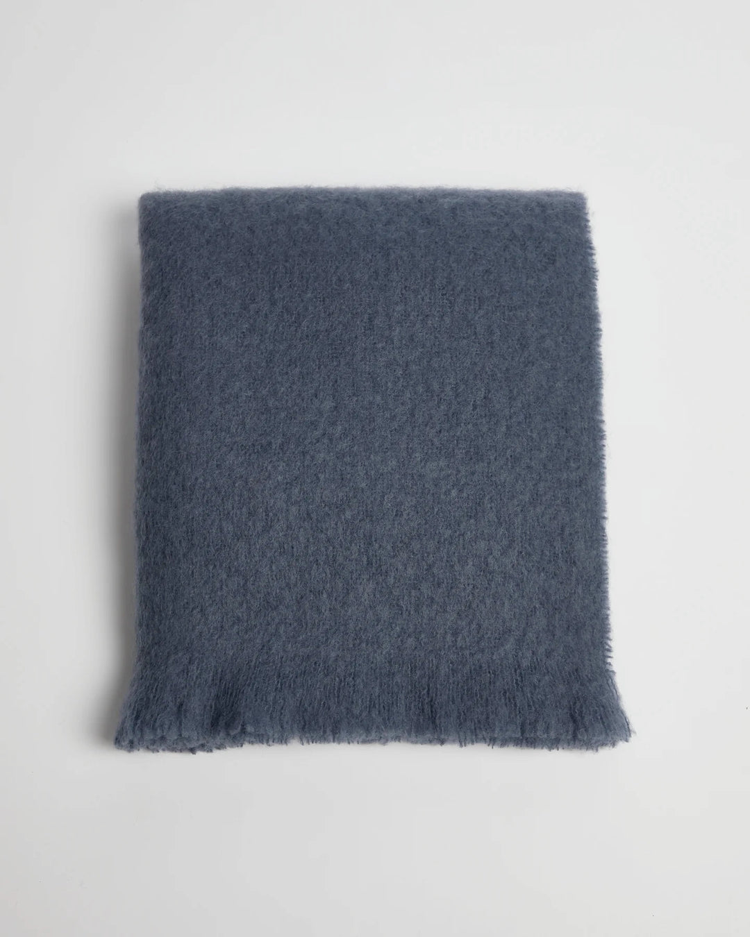 Blue textured mohair blanket folded on a light gray background