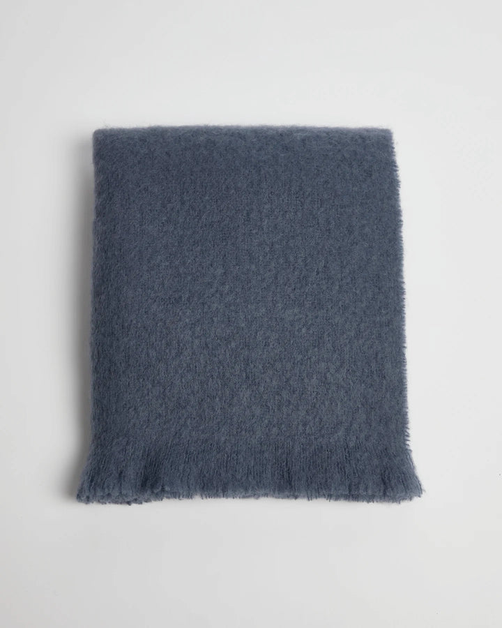 Blue textured mohair blanket folded on a light gray background