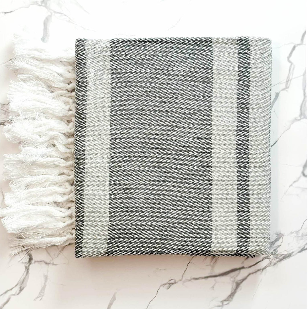 Black and white striped towel with tassels on a marble surface