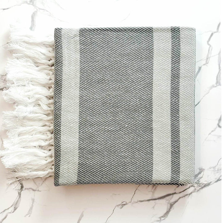 Black and white striped towel with tassels on a marble surface