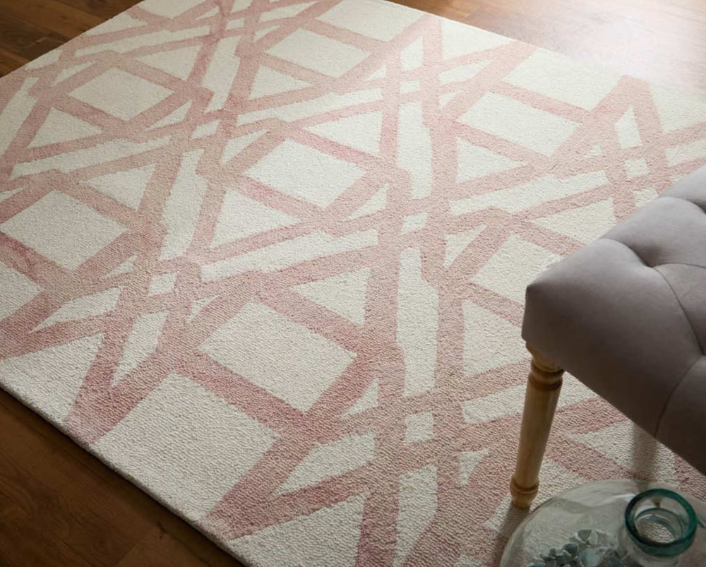 Patterned pink and white rug on a wooden floor with a chair partially visible.