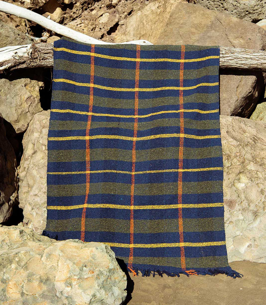 Plaid blanket with blue, green, and orange pattern draped over a rock