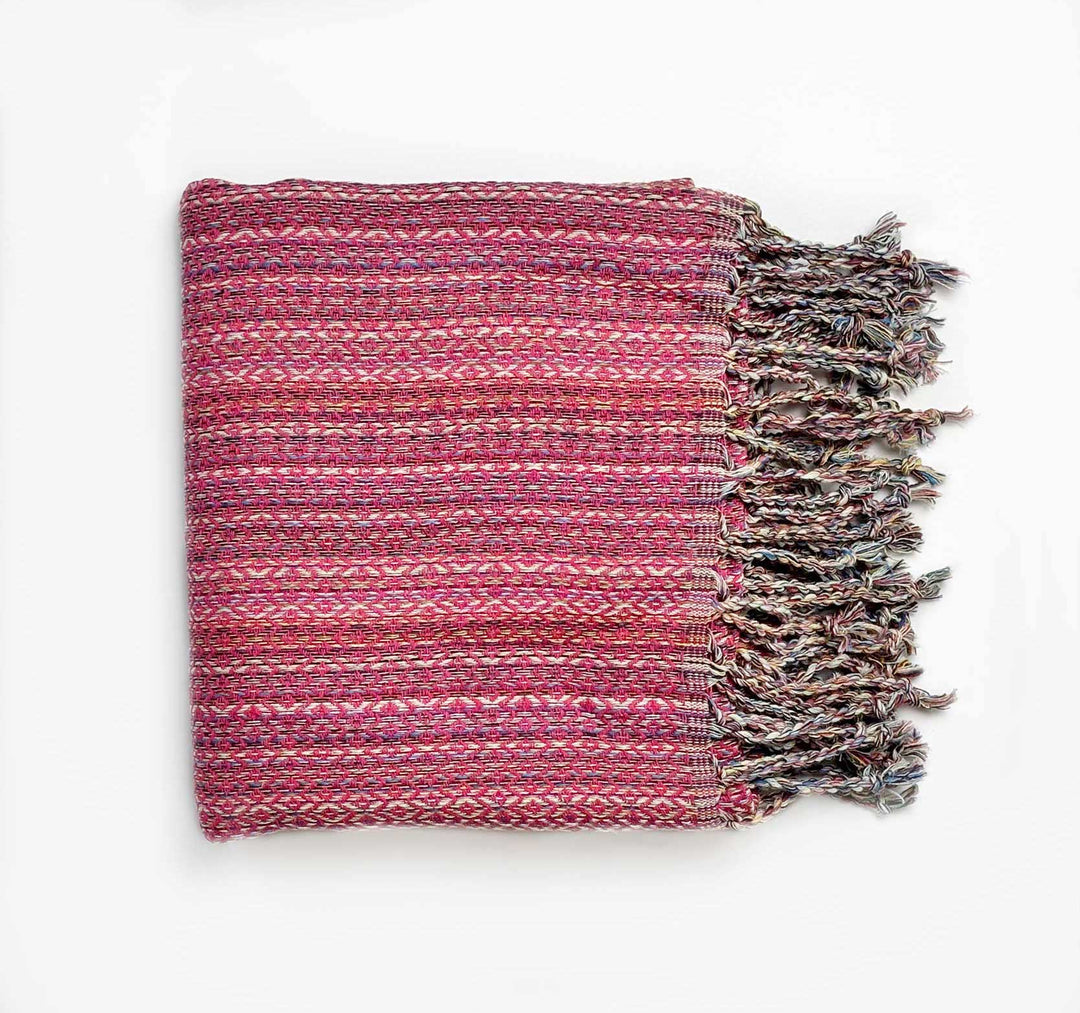 Woven pink and purple blanket/turkish towel with fringes on a white background